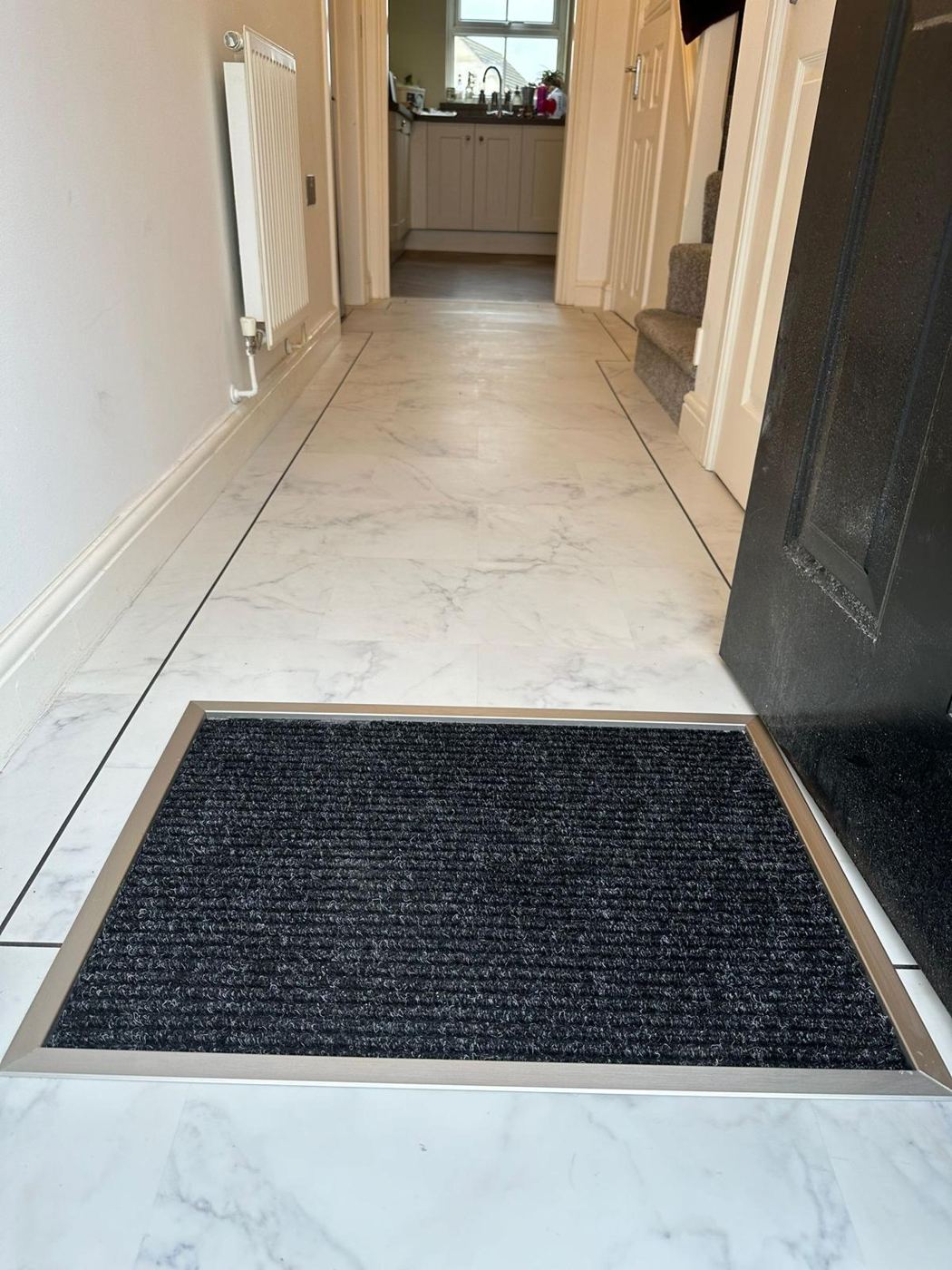 Marble-look floor in a hallway with a sunken door mat