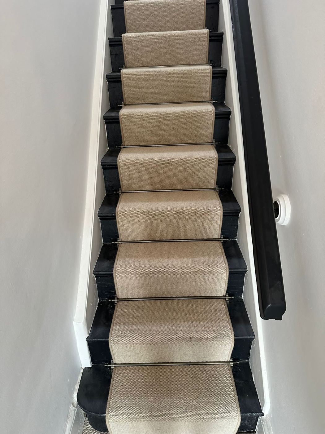 Natural runner with a black bound edge on white stairs