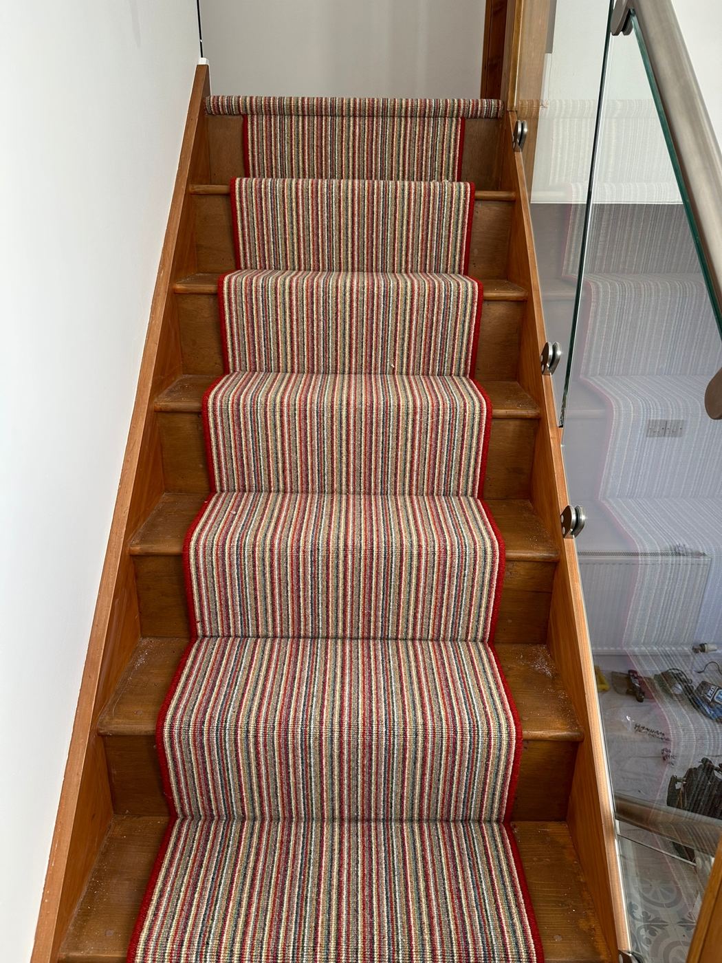 Striped runner with red edges on wooden stairs