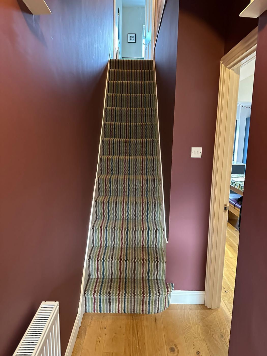 Tartan stair carpet against a deep red wall